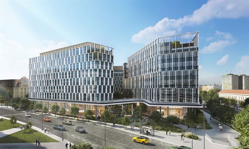 Modern office buildings with glass facades, landscaped grounds, and a street with cars under blue sky.